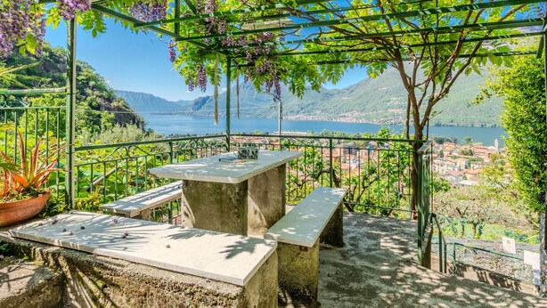 A terrace with a table and benches, overlooking a lake and a town. - Castello by Interhome (Dervio)