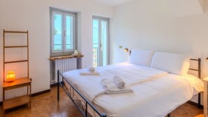 A bedroom with a bed, a bedside table, a heater, and a window. - Castello by Interhome (Dervio)