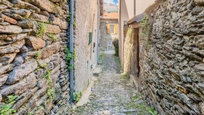 A narrow cobblestone alley flanked by stone buildings with traditional shutters and a clear sky above. - Castello by Interhome (Dervio)