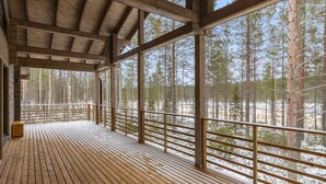 Puinen terassi, jossa on kaide, ja jolta avautuu näkymä lumiseen metsään.