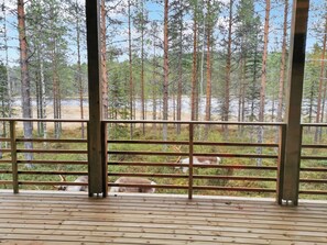 A wooden deck with metal railings overlooking a forested area with deer. - Villa korpi by Interhome (Kuusamo)