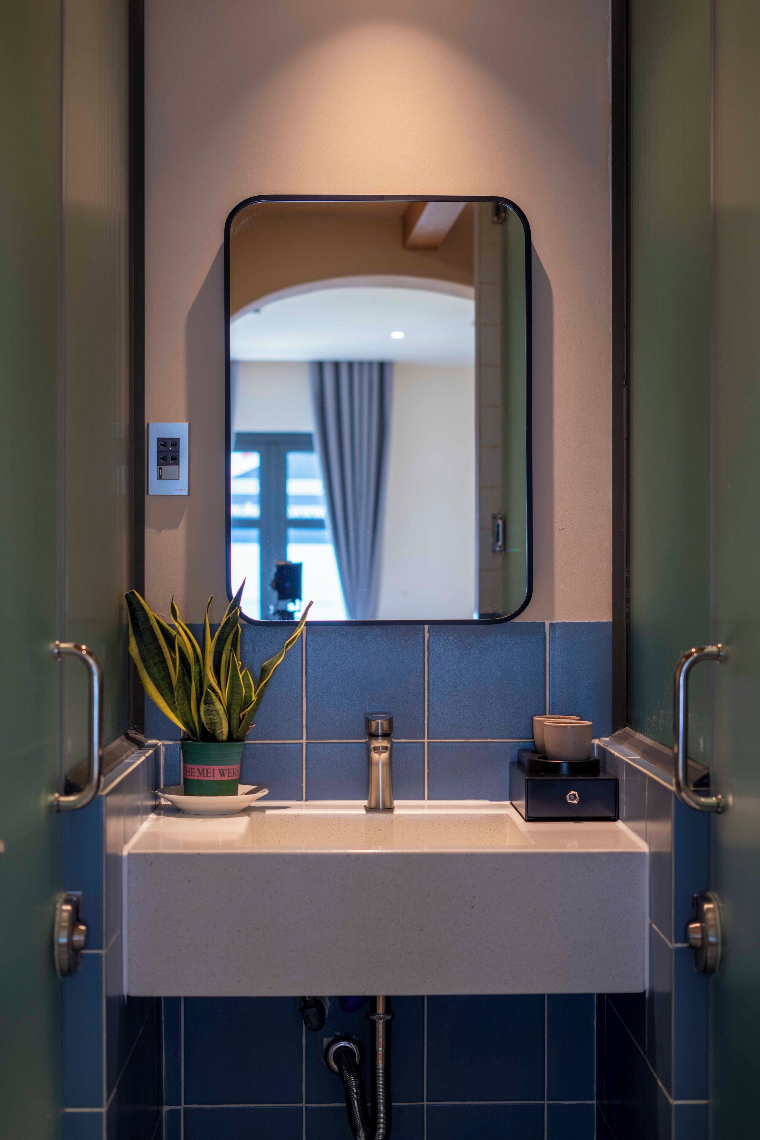 Een badkamer met een wastafel, spiegel en een plant in een pot.