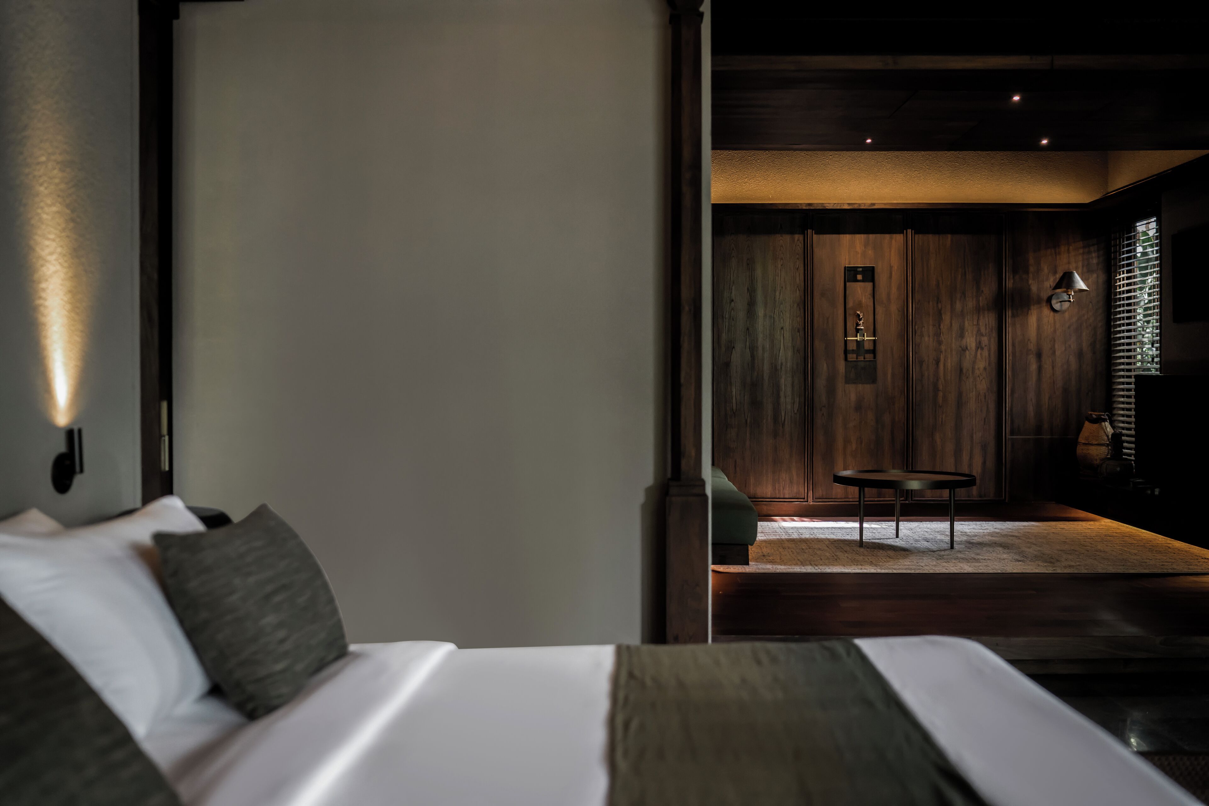 A modern bedroom with a large bed, a small table, and a wooden wall.