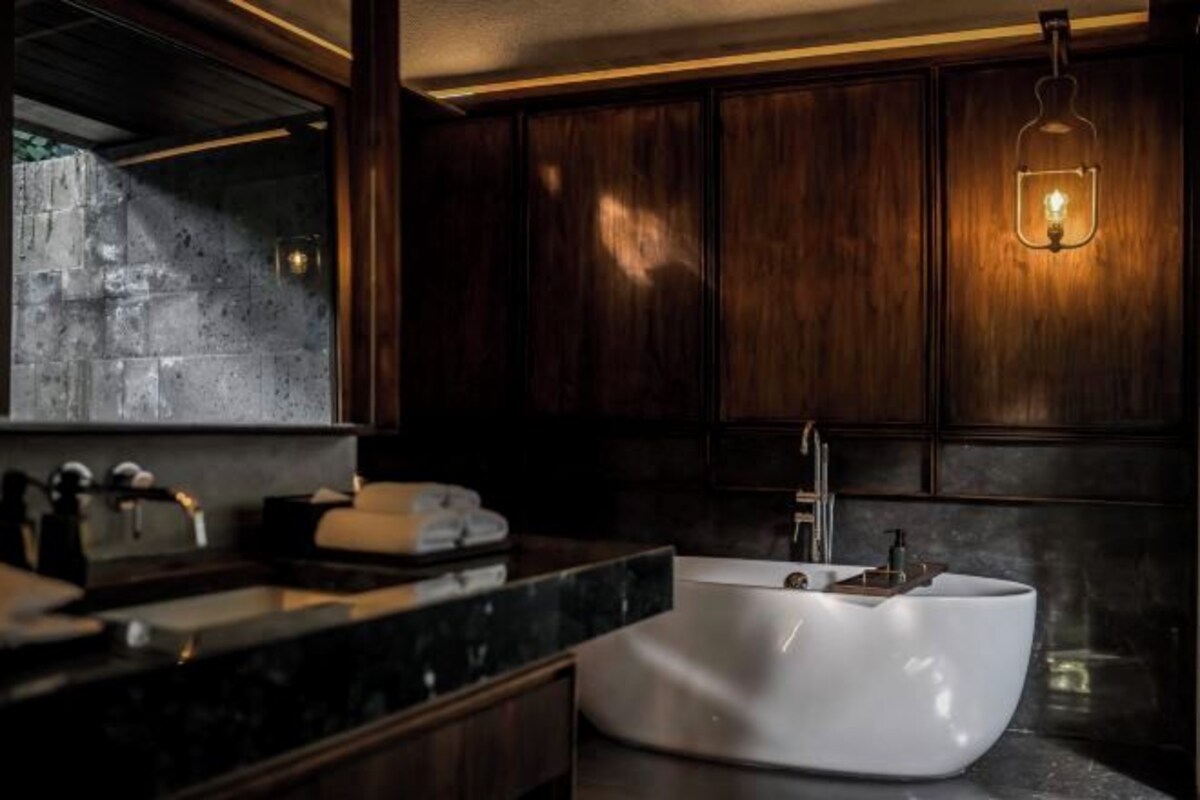 Ein modernes Badezimmer mit einer freistehenden Badewanne, dunklen Holzschränken und einer Marmorarbeitsplatte.