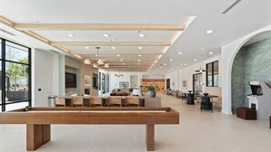 A spacious lobby with a long wooden bench, a reception desk, and a seating area with tables and chairs.