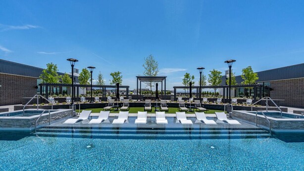 A swimming pool with lounge chairs and a gazebo, surrounded by brick walls and trees.