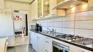 Una cocina moderna con armarios blancos, un horno Bosch, una estufa a gas y un microondas.