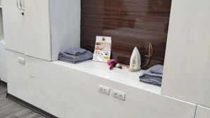 Een kamer met een witte garderobe, een houten kast en een aanrecht met een brochure en een haardroger.