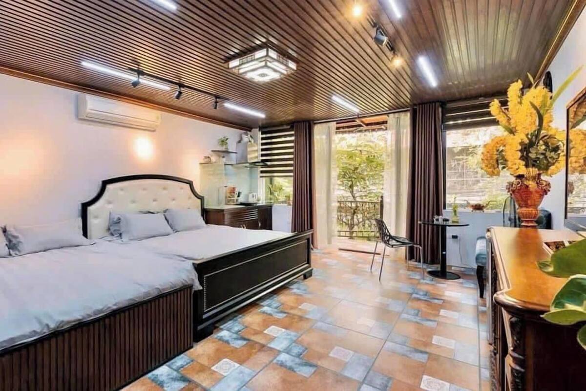 A modern bedroom with a bed, bedside table, and a view of the outdoors.