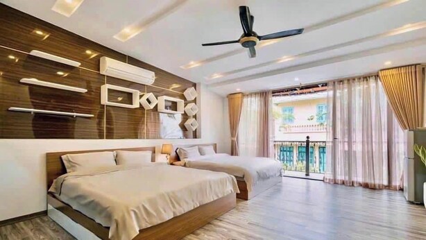 Een moderne hotelkamer met een groot bed, een plafondventilator en een balkon met gordijnen.