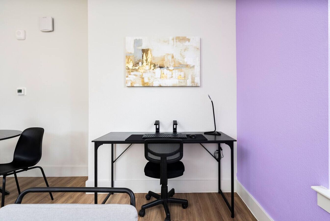 Un espace de bureau moderne, comprenant un bureau, une chaise et un tableau accroché au mur.