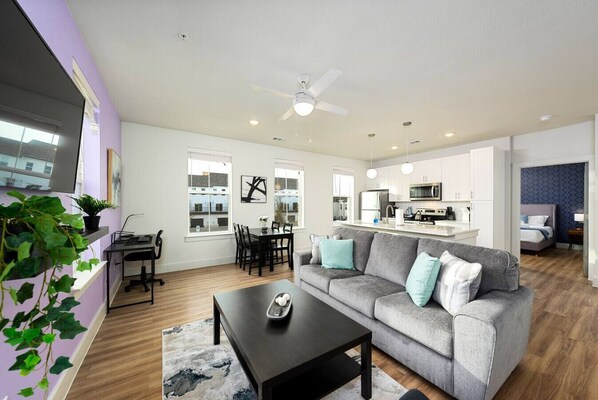A modern living room with a grey sofa, a black coffee table, and a dining area with a table and chairs.