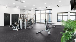 A modern gym with various exercise machines, large windows, and a potted plant. - Perfect Environment w toptier furnishing/amenities (Pflugerville)