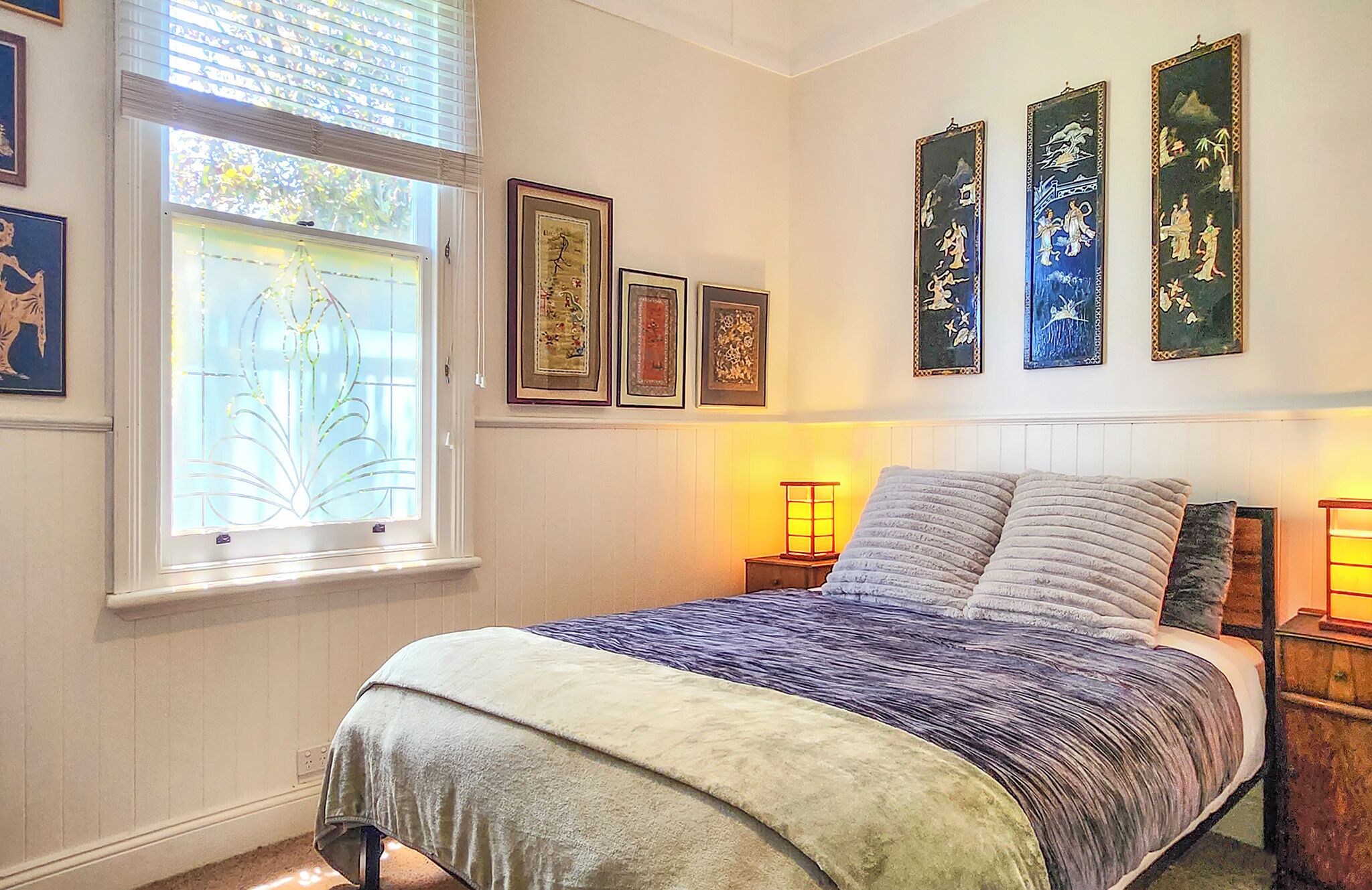Un dormitorio con cama, ventana con persianas y una obra de arte en la pared.