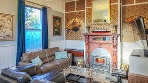 Een woonkamer met een open haard, leren bank, een kroonluchter en decoratieve wandpanelen.