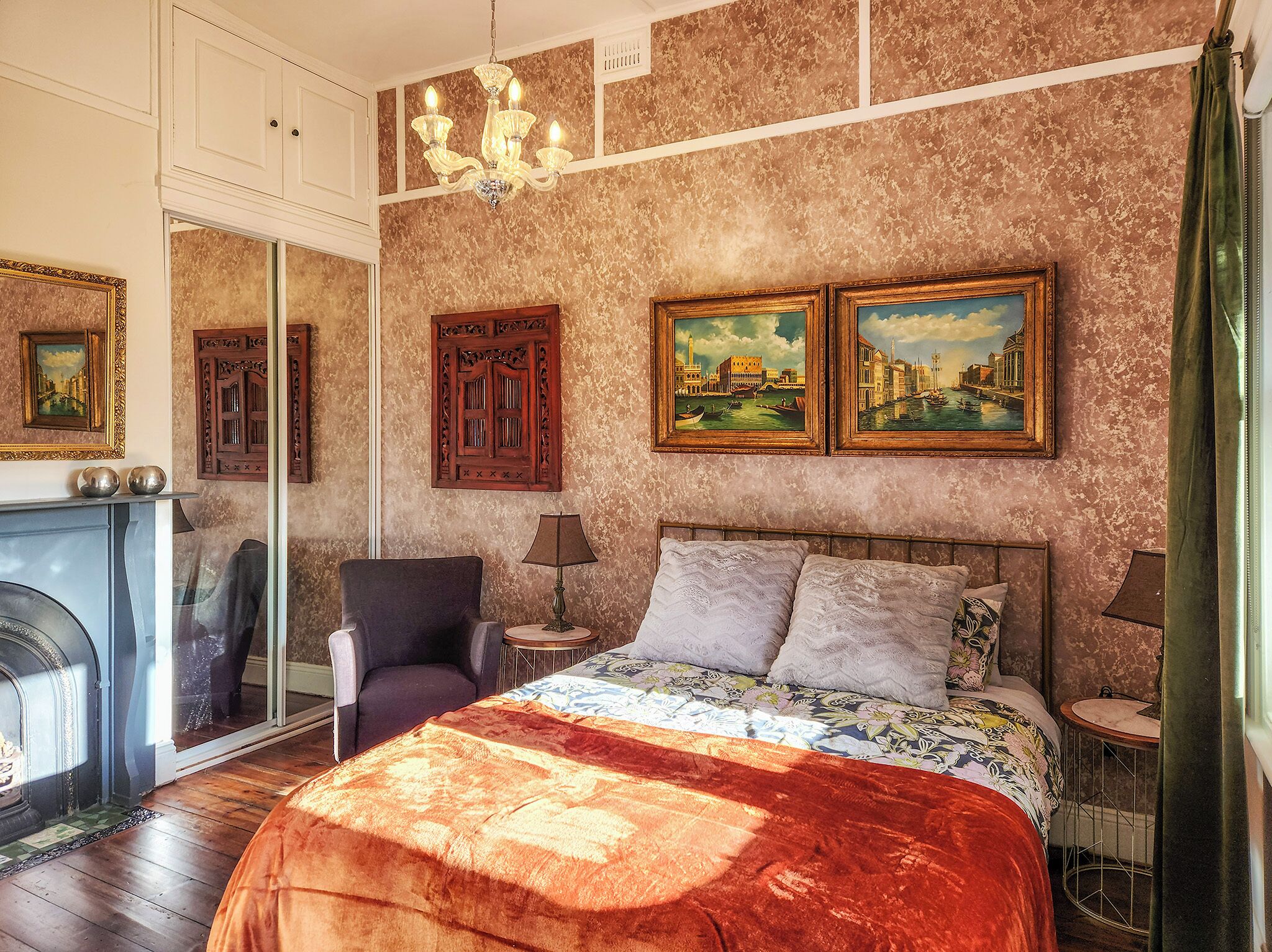 Ein Schlafzimmer mit einem Bett, einem Sessel, einer Lampe, einem Kamin und zwei Bildern an der Wand.