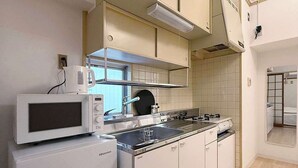 Een keuken met witte kasten, een magnetron, een fornuis en een spoelbak.