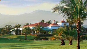 A golf course with a clubhouse featuring domed roofs and palm trees.
