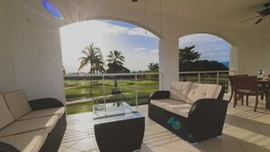 Un balcón amplio con vistas a un campo de golf, amueblado con un sofá y una mesita de centro.