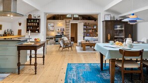 Et rummeligt køkken med høje lofter, ovenlysvinduer og et spiseområde med en blå måtte.
