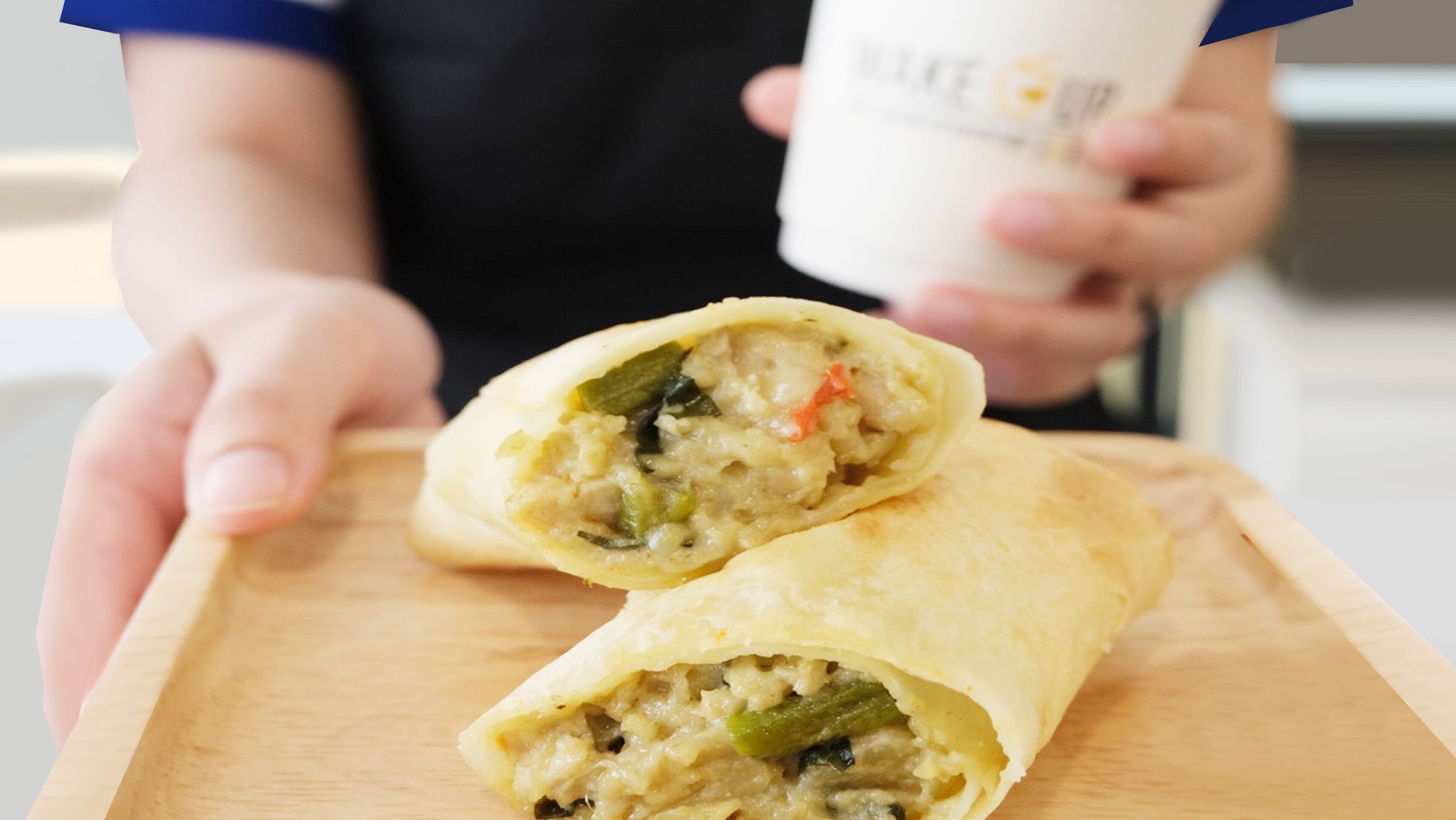 A person holding a burrito with visible ingredients like vegetables and meat.