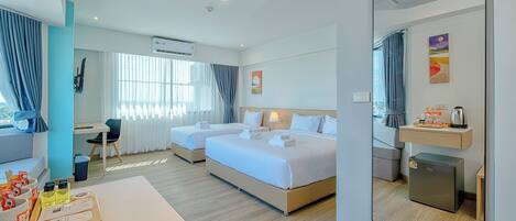 A hotel room with two beds, a desk, a chair, a small kitchenette, and a bathroom.