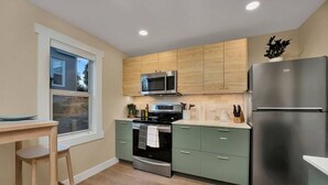 A modern kitchen with wooden cabinets, stainless steel appliances, and a window overlooking the outdoors.