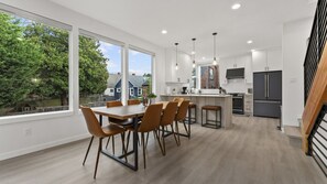 Une cuisine moderne dotée d’un îlot central, de grandes fenêtres et offrant une vue sur un quartier résidentiel.