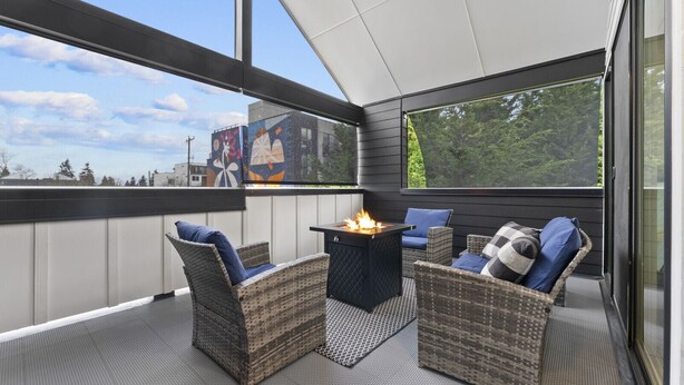 A covered outdoor seating area with wicker furniture and a central fire feature. - Ballard Hangout - Arcade, Covered deck, Sleeps 10! (Seattle)
