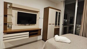 Un dormitorio moderno con una cama grande, un televisor montado en la pared y un armario.