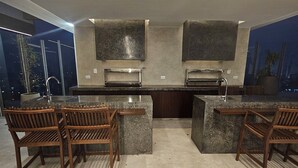 Una cocina moderna con encimeras de granito, hornos integrados y un amplio ventanal con vistas a la ciudad.