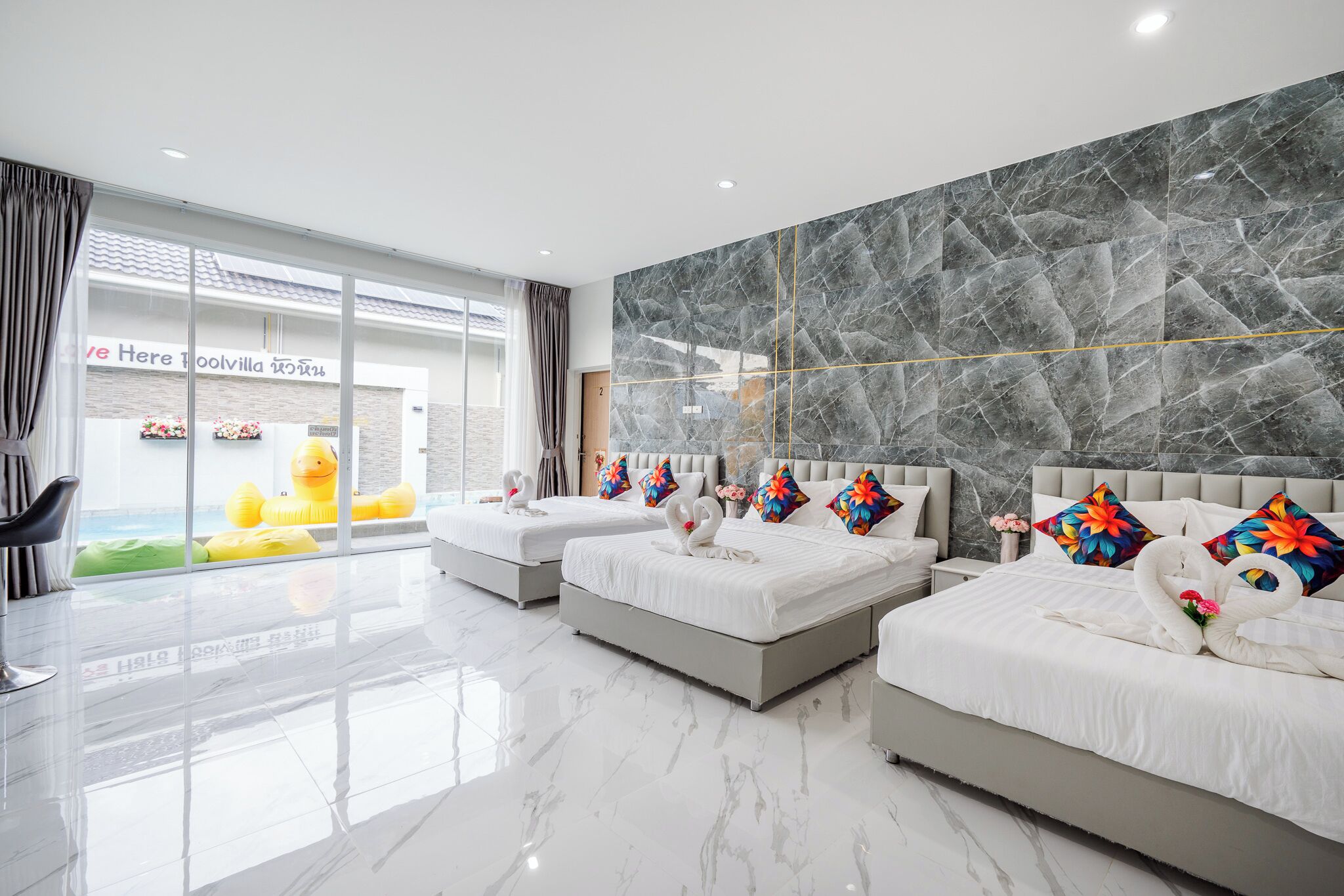 Une chambre d’hôtel avec deux lits, des murs en marbre et une grande fenêtre donnant sur l’extérieur.