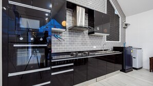 Una cocina moderna con armarios negros, electrodomésticos de acero inoxidable y salpicadero de ladrillo.