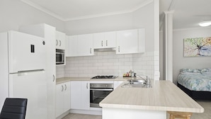 Una cocina moderna con armarios blancos, horno empotrado, microondas y estufa a gas.