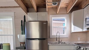 Eine moderne Küche mit Holzbalken, einem Edelstahl-Kühlschrank, einer Spüle und einem Herd.