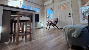 Ein großzügiger Loft-Raum mit hoher Decke, Holzbalken, einem großen Deckenventilator, einer Essecke mit Bar und einer gemütlichen Sitzecke mit Sessel und Sofa.