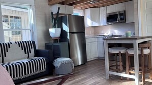 Eine moderne Küche mit weißen Schränken, einem Edelstahlkühlschrank und einer Holzbalkendecke.