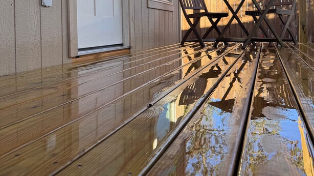Eine Holzterrasse mit einer Bank und einer Tür.