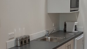 A modern kitchen with white cabinets, a stainless steel sink, and a microwave.