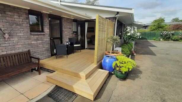 A covered outdoor seating area with a wooden bench, a table, and chairs.