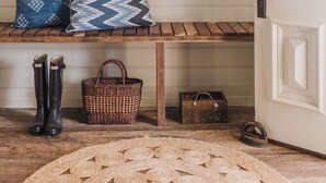 A cozy room with a bench, a hat, boots, a basket, and a door.