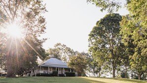 A house with a porch, surrounded by trees and a grassy lawn.