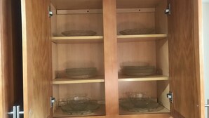 A wooden cabinet with three shelves, each holding a clear glass bowl. - Charming 2-bedroom apartment in Pleasant Valley Stream with AC, WiFi (Valley Stream)