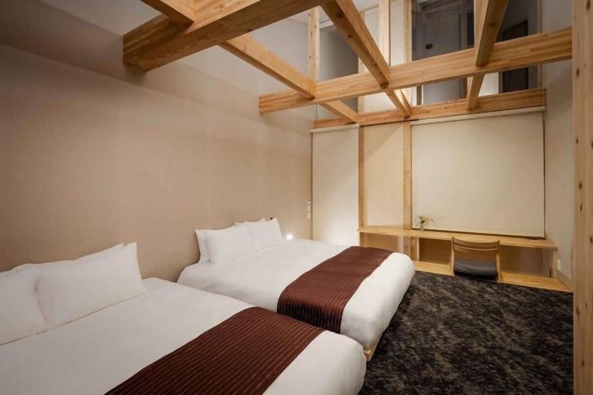 Una habitación de hotel con dos camas, techo de madera y un ventanal grande.