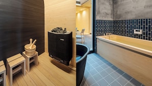 Un sauna aux murs en bois, avec un appareil de chauffage noir et une petite table en bois sur laquelle se trouvent un bol et des cuillères en bois.