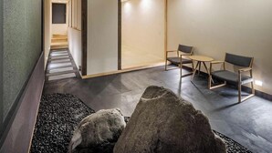 Un intérieur moderne avec un plafond haut, des poutres en bois et un espace salon agrémenté de tables et de chaises.