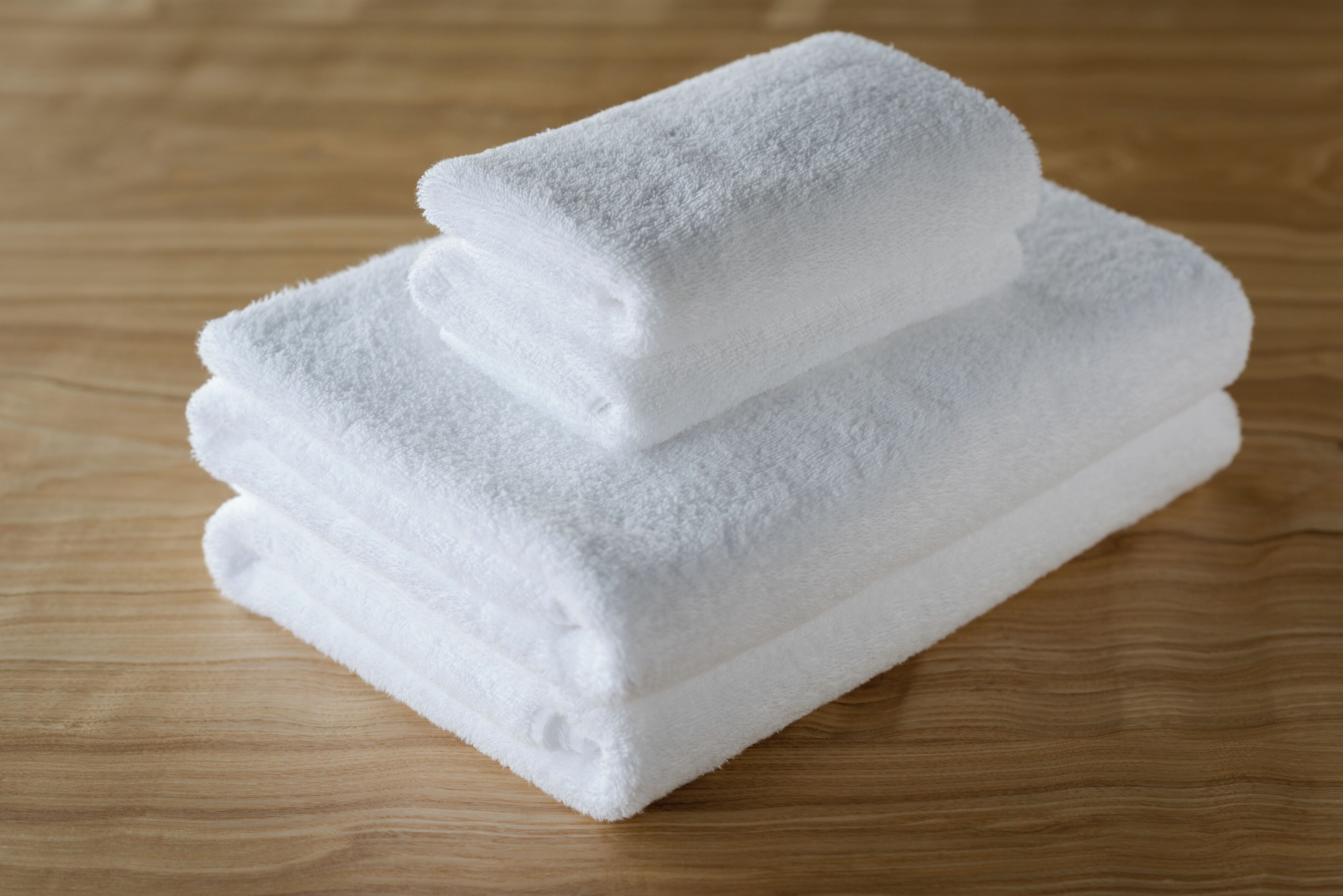 A stack of white towels on a wooden surface.