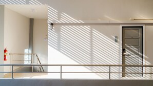 A modern hotel corridor with a fire extinguisher, a metal railing, and a door with a number plate. - B2 Chiang Rai Resort Boutique & Budget Hotel (Chiang Rai)