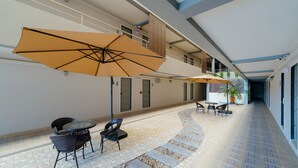 A corridor with outdoor seating, including tables and chairs, and large umbrellas providing shade. - B2 Chiang Rai Resort Boutique & Budget Hotel (Chiang Rai)