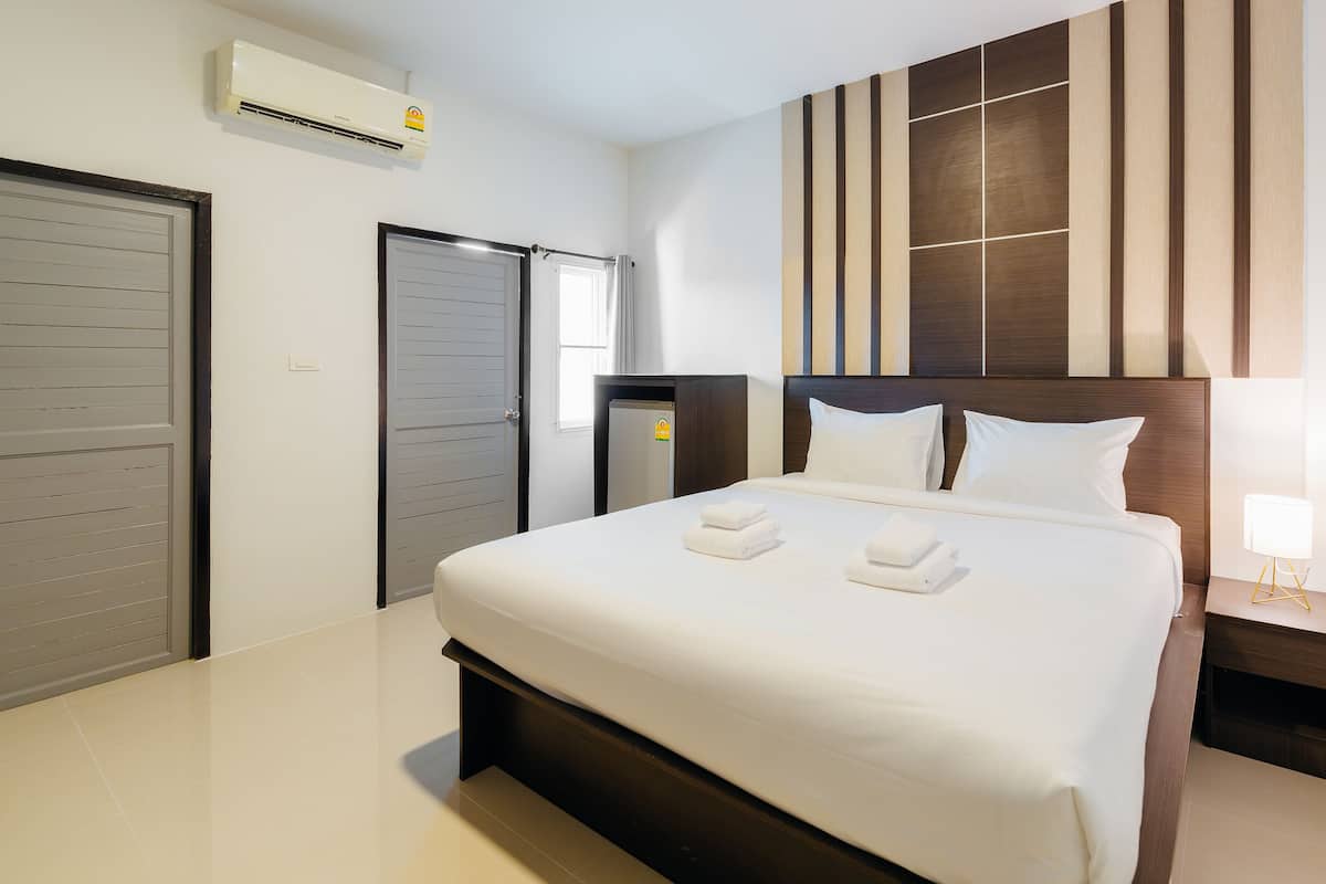 A hotel room with a large bed, a bedside table with a lamp, a wardrobe, and a door.